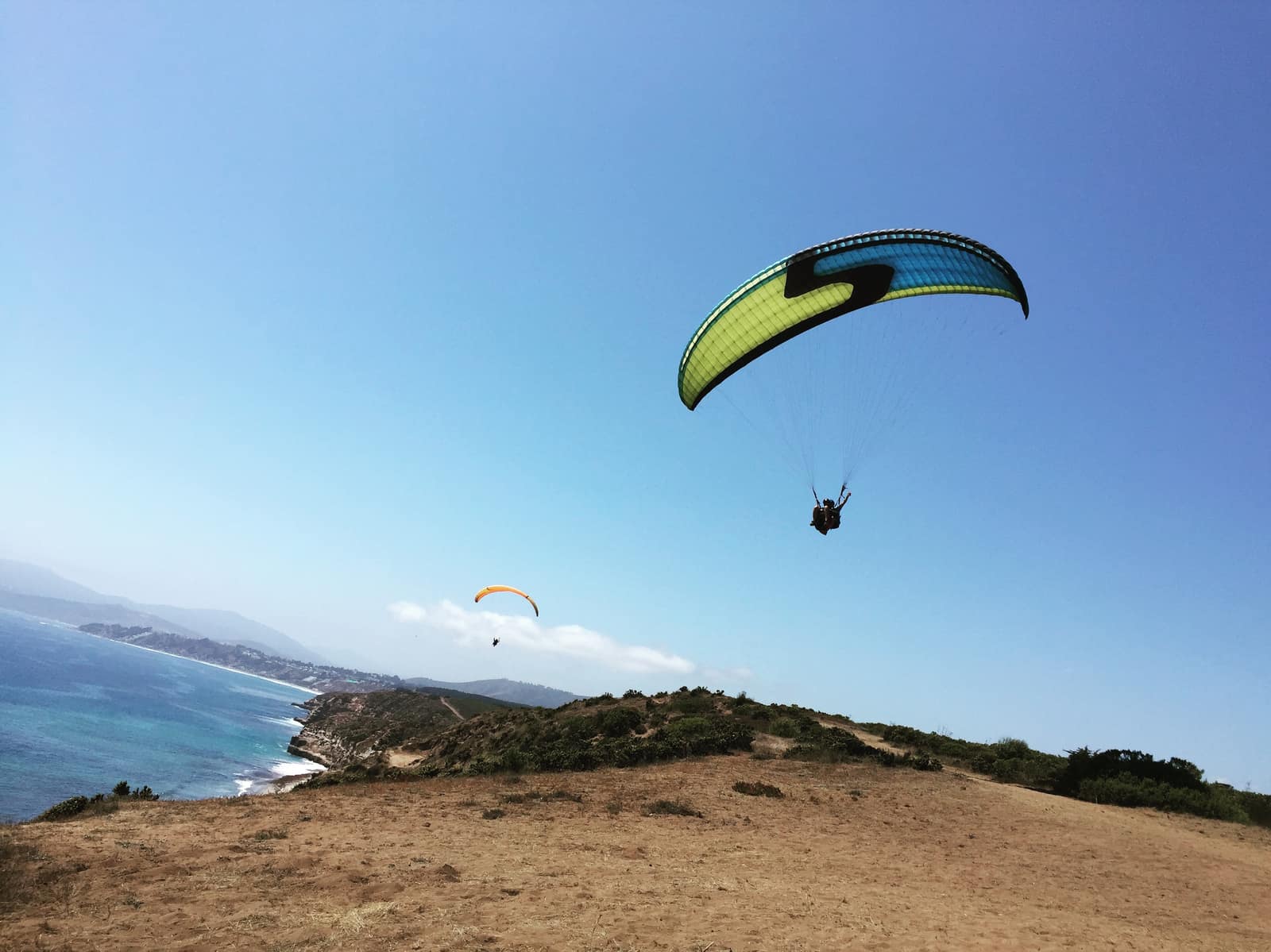 Dos parapentes volando sobre los acantilados de Cerro Tacna, Maitencillo